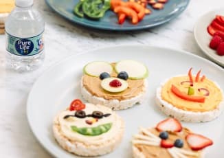 Plates of the "Smiley Rice Cake" recipe with an 8 fluid ounce bottle of Pure Life purified water.